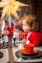 Christmas miracle, happiness, little curly girl blows out candle on table decorated with New Year decorations at home Royalty Free Stock Photo