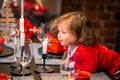 Christmas miracle, happiness, little curly girl blows out candle on table decorated with New Year decorations at home Royalty Free Stock Photo