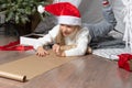 Christmas helper child writing letter to Santa Claus in red hat. smiling girl making wish list or letter to santa at Royalty Free Stock Photo