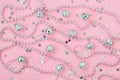 Christmas mirror balls and bead garland on a pastel pink background with silver stars. Festive flat lay for Christmas and New Year
