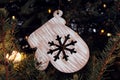Christmas mitten decorated with a snowflake, carved from wood, hanging on a festive fir tree, close-up Royalty Free Stock Photo