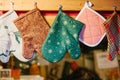 Christmas mittens potholders hang in kitchen against the background of blurry kitchen appliances.
