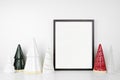 Christmas mock up with black frame and tree decor on a white shelf against a white wall Royalty Free Stock Photo