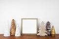 Christmas mock up with wood frame and rustic tree decor on a shelf against a white wall