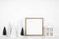 Christmas mock up with wooden frame, lantern and tree decor on a white shelf against a white wall Royalty Free Stock Photo