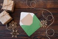 Christmas mockup holiday letter Blank paper in green envelope with wooden snowflakes and gift boxes on wood table, with space for Royalty Free Stock Photo