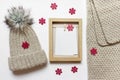 Christmas mockup with knitted hat and scarf, wooden frame and many red wooden snowflakes