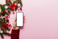 christmas mockup with space for text. christmas advertising, app template. hand holding phone with empty screen on table Royalty Free Stock Photo