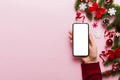 christmas mockup with space for text. christmas advertising, app template. hand holding phone with empty screen on table Royalty Free Stock Photo