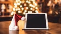 Christmas Mockup: Tablet with Santa Hat on Winter Holiday Background. Royalty Free Stock Photo