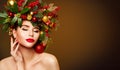 Christmas Model Beauty in Decorated Fir Tree Wreath. Woman Face and Body Skin Care. Girl with Red Lips Make up Touching Cheek Royalty Free Stock Photo