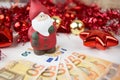 Christmas money business concept: a statuette of Santa Claus on some fifty euro banknotes with red and gold baubles and wreath