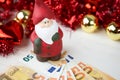 Christmas money business concept: a statuette of Santa Claus on some fifty euro banknotes with red and gold baubles and wreath