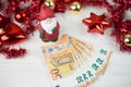 Christmas money business concept: a statuette of Santa Claus on some fifty euro banknotes with red and gold baubles and wreath