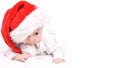 Christmas mood baby. Cute four month old caucasian baby in a red Santa Claus hat lying on stomach cunning look leer on a white