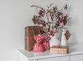 Christmas mood. Gifts, cranberry branches in a vase with paper toys on the dresser