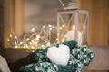 Christmas mood with snowball in shape of heart in hands with mittens outdoor candle holder with burning candle