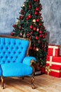 Christmas morning, copy space. Classic apartments with blue buttoned sofa, decorated fir tree and red gift boxes.