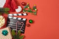Christmas movie night and party concept with popcorn, santa hat, decorations and movie clapper board on red background. Top view Royalty Free Stock Photo