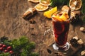 Christmas mulled red wine with spices and fruits in tall glass on wooden rustic table. Traditional Christmas or NewYear warming