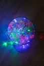 Christmas multicolored red green blue garland lights from LED bulbs in glass jar on wooden table background. Top view, vertical Royalty Free Stock Photo