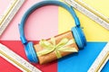 Christmas music gift concept. Headphones and gift boxes and wooden photo frame on colorful background.