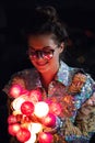 Happy woman wearing glowing jacket with sequins is holding light balls in her hands