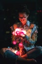 Happy woman wearing glowing jacket with sequins is holding light balls in her hands