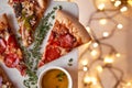 Christmas and New Year atmosphere. Hot Italian pizza with melting tomato, pepperoni and cheese on a white marbel cutting