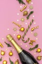 Christmas and New Year background. Champagne bottle, golden christmas balls, festive ribbons, fir branches, star confetti on pink Royalty Free Stock Photo