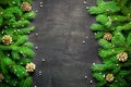 Christmas and New Year background. Christmas tree branch on a black background. Cones and fur-tree toys. View from above. Royalty Free Stock Photo