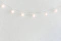Christmas New Year Background. Hanging Pastel Golden Cotton Balls Garland White Wall Background. Scandinavian Style. Lights