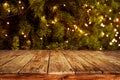 Christmas and New year background with empty dark wooden deck table over christmas tree and blurred light bokeh. Royalty Free Stock Photo