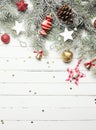 Christmas or New Year background: fur-tree branches, colorful glass balls, decoration and glittering stars on white wood Royalty Free Stock Photo