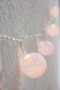 Christmas New Year Background. Hanging Pastel Golden Cotton Balls Garland White Wall Background. Scandinavian Style. Glittering Li