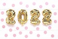 Christmas or New Year background. 2022, made of golden balls, on a white wooden background, with pink confetti. Postcard or Royalty Free Stock Photo