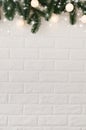 White brick wall with fir branches and Christmas lights in the form of white balls Royalty Free Stock Photo