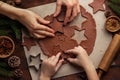 Christmas and New Year bakery. Close up of kids and female hands cooking traditional gingerbread cookies. Wooden kitchen table