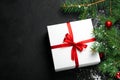 Christmas, New Year black stylish background with a branch of fir tree, white gift box red bow and balls. Flat lay Royalty Free Stock Photo