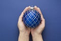 Christmas or new year blue background with female hands holding decorative winter bauble over blue background, isolated Royalty Free Stock Photo
