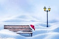 Christmas New Year card. A lonely bench, a Santa hat and a lantern against a background of pure white snow. Winter magic land.