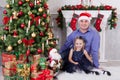 Christmas or New year celebration. Father and daughter sit near the Christmas tree. Father have a Santa Claus hat on his head. A f Royalty Free Stock Photo