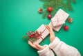 Christmas or New Year celebration green paper festive background with female hands holding wrapped present box Royalty Free Stock Photo