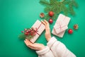 Christmas or New Year celebration green paper festive background with female hands holding wrapped present box Royalty Free Stock Photo