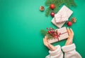 Christmas or New Year celebration green paper festive background with female hands holding wrapped present box Royalty Free Stock Photo