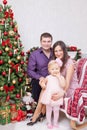 Christmas or New year celebration. Happy young family sitting in chair near Christmas tree with xmas gifts. A fireplace with chris Royalty Free Stock Photo