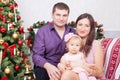 Christmas or New year celebration. Happy young family sitting in chair near Christmas tree with xmas gifts. A fireplace with chris Royalty Free Stock Photo