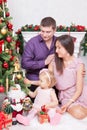 Christmas or New year celebration. Happy young family sitting in chair near Christmas tree with xmas gifts. A fireplace with chris Royalty Free Stock Photo