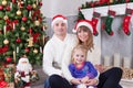 Christmas or New year celebration. Happy young family sitting near Christmas tree with xmas gifts. A fireplace with christmas stoc Royalty Free Stock Photo
