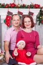 Christmas or New year celebration. Happy young family sitting near Christmas tree with xmas gifts. A fireplace with christmas stoc Royalty Free Stock Photo